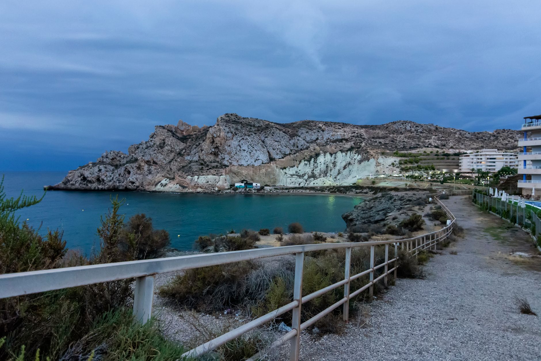 View of Águilas coast with path and railing leading to the rocky beach.