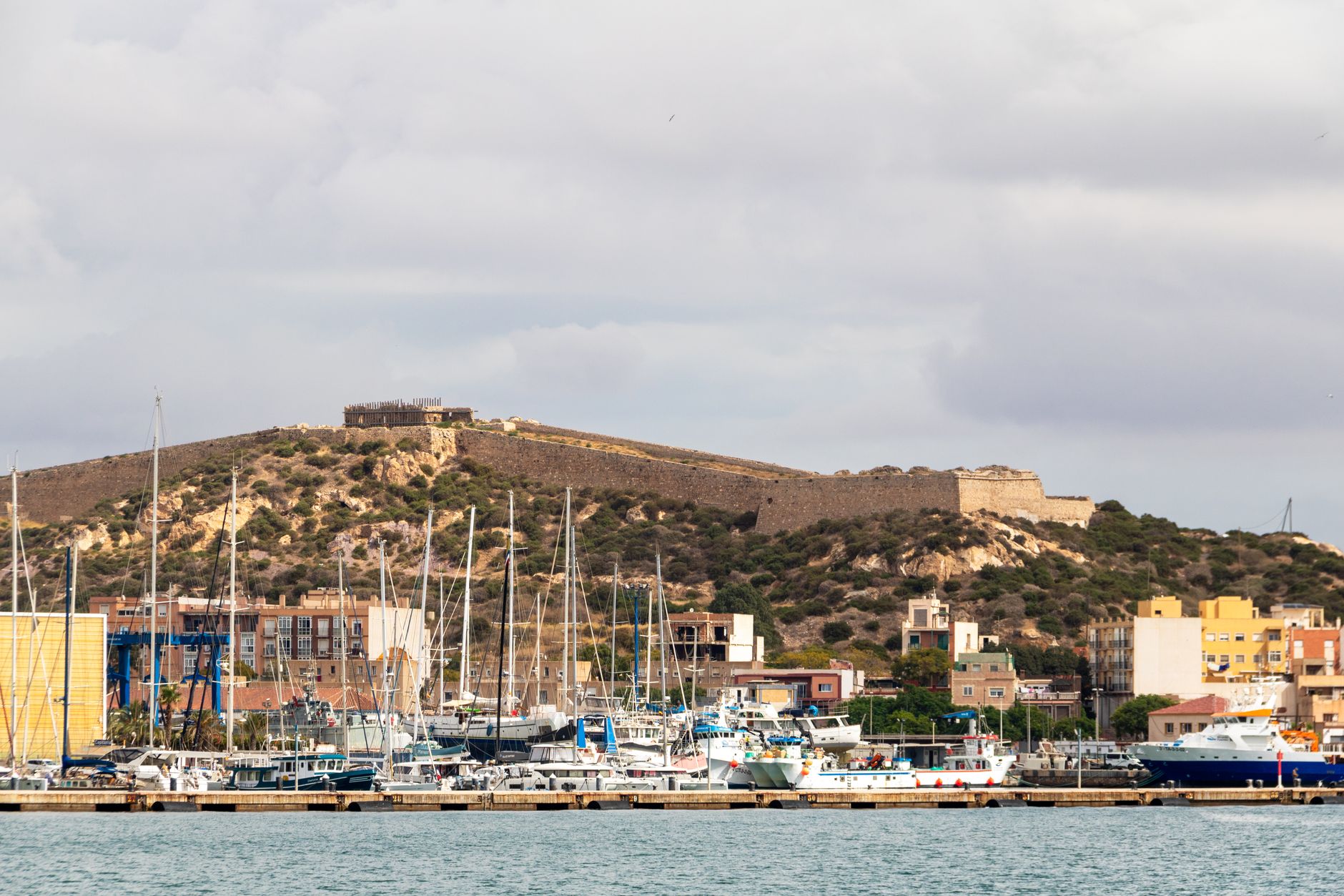 A harbor with yachts and a historic fortress in Cartagena, Spain.