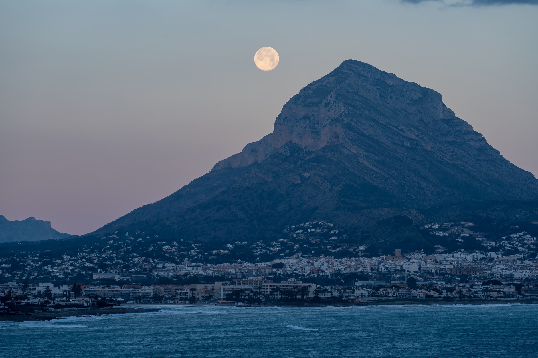 Capture the beauty of the full moon rising over Montgó Mountain in Dénia, Spain.