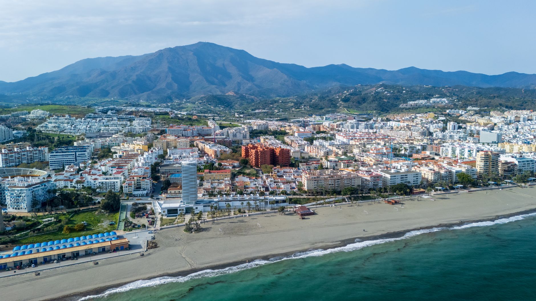 Aerial view of Estepona's beachfront cityscape with mountains in the background.