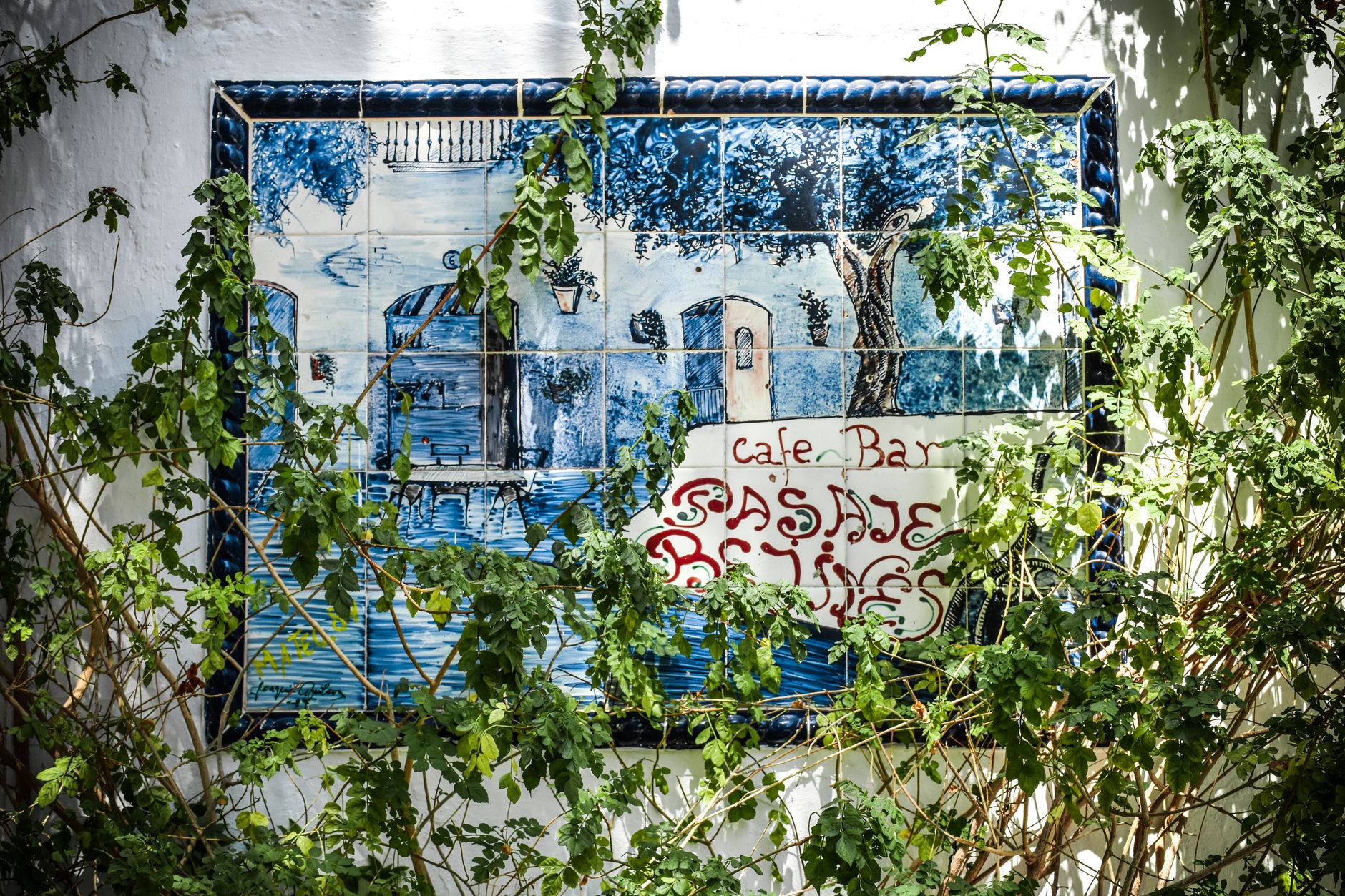 Outdoor wall art depicting a Spanish café surrounded by greenery in Estepona.