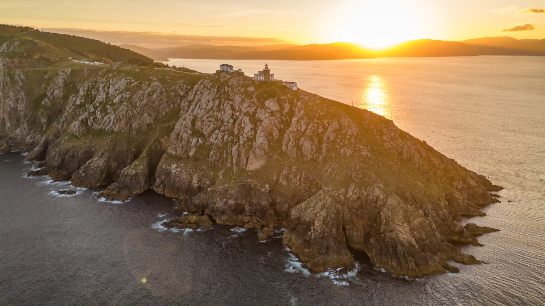 Aerial view of the Faro de Fisterra lighthouse on Cape Finisterre at sunrise, Costa de la Muerte, Galicia, northern Spain. The final destination of the Camino de Santiago pilgrimage route