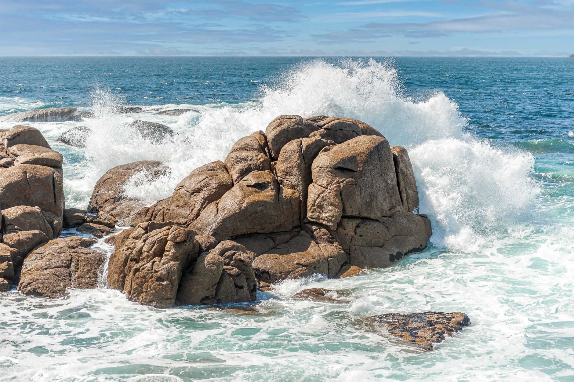 Dramatic scene of crashing sea waves on rugged rock formations in Fisterra, Spain's Galician coast.