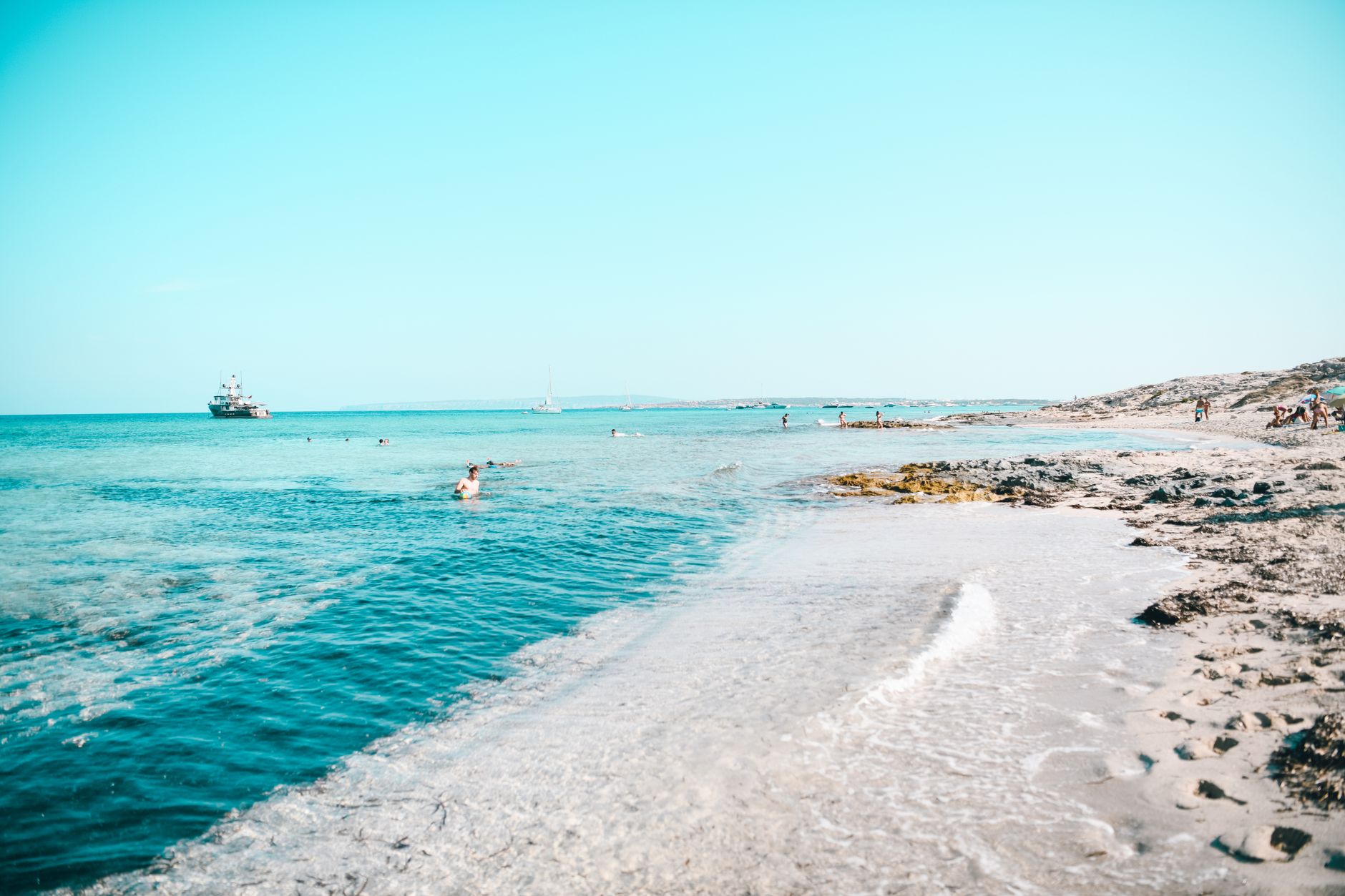 Relaxing beach scene in Formentera, Spain with clear blue waters and a horizon.