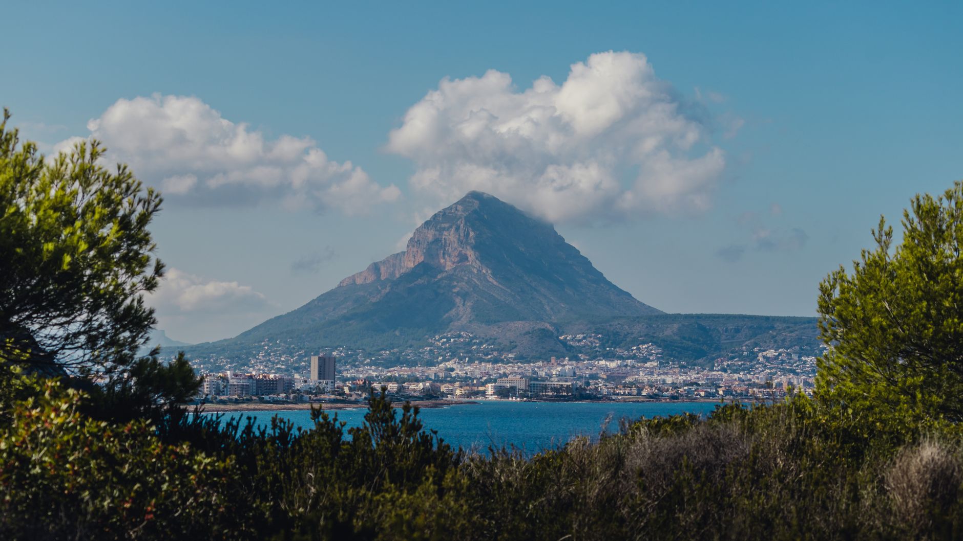 Landscape of Montgó Mountain in Javea, surrounded by sea and greenery under a clear sky.