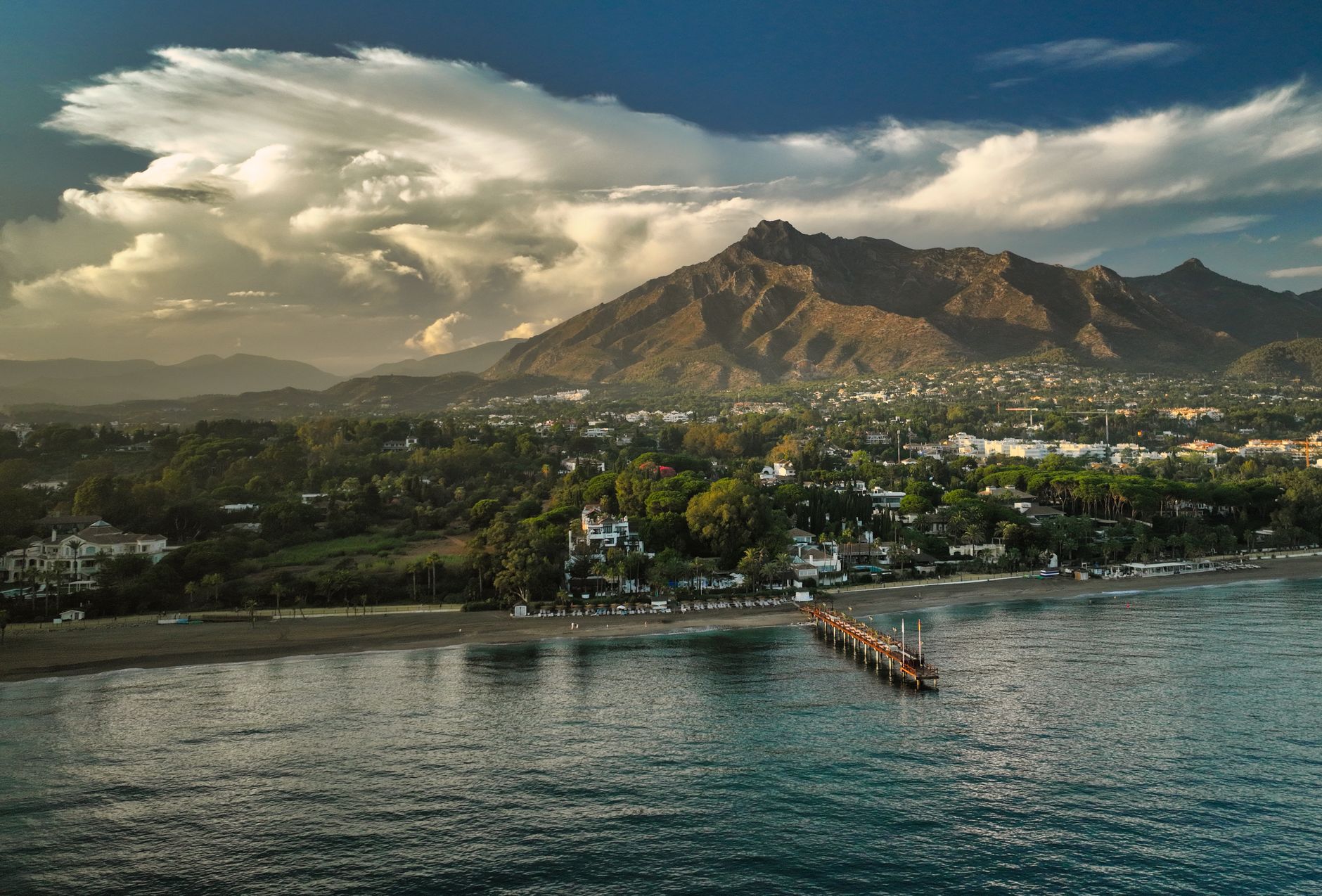 A aerial view of Marbella's coastline, greenery, and mountains.
