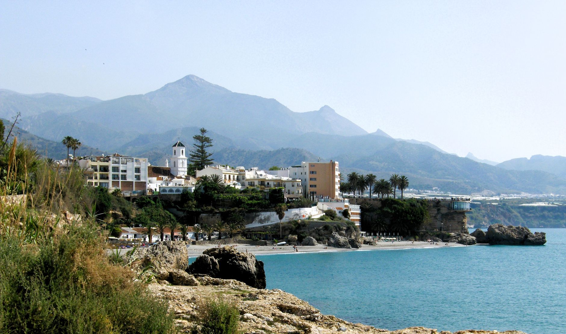 Coastal town of Nerja with mountains and clear blue sea.