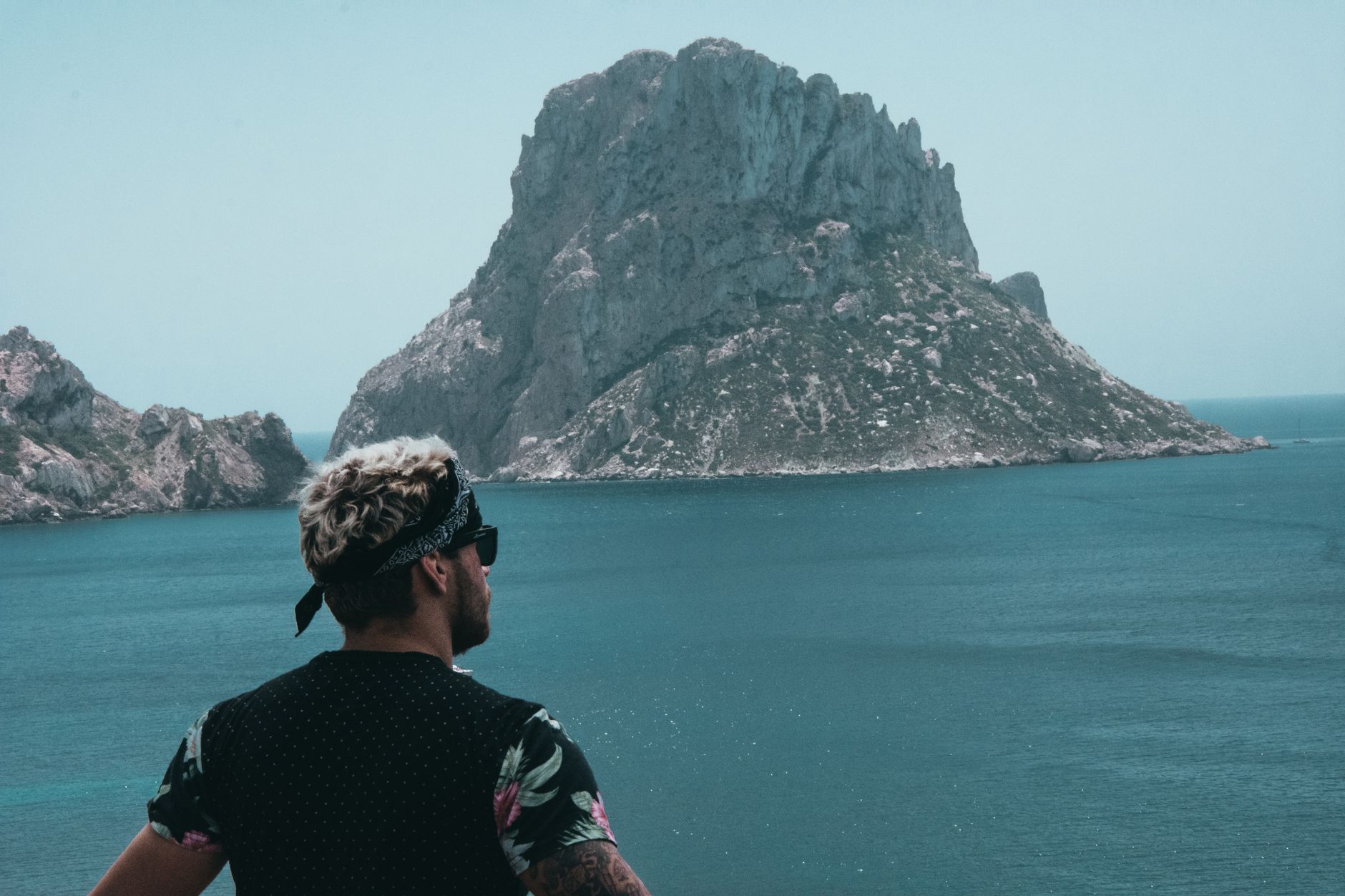 A man with a bandana observes the rock island Es Vedrà from Sant Josep de sa Talaia, Ibiza.