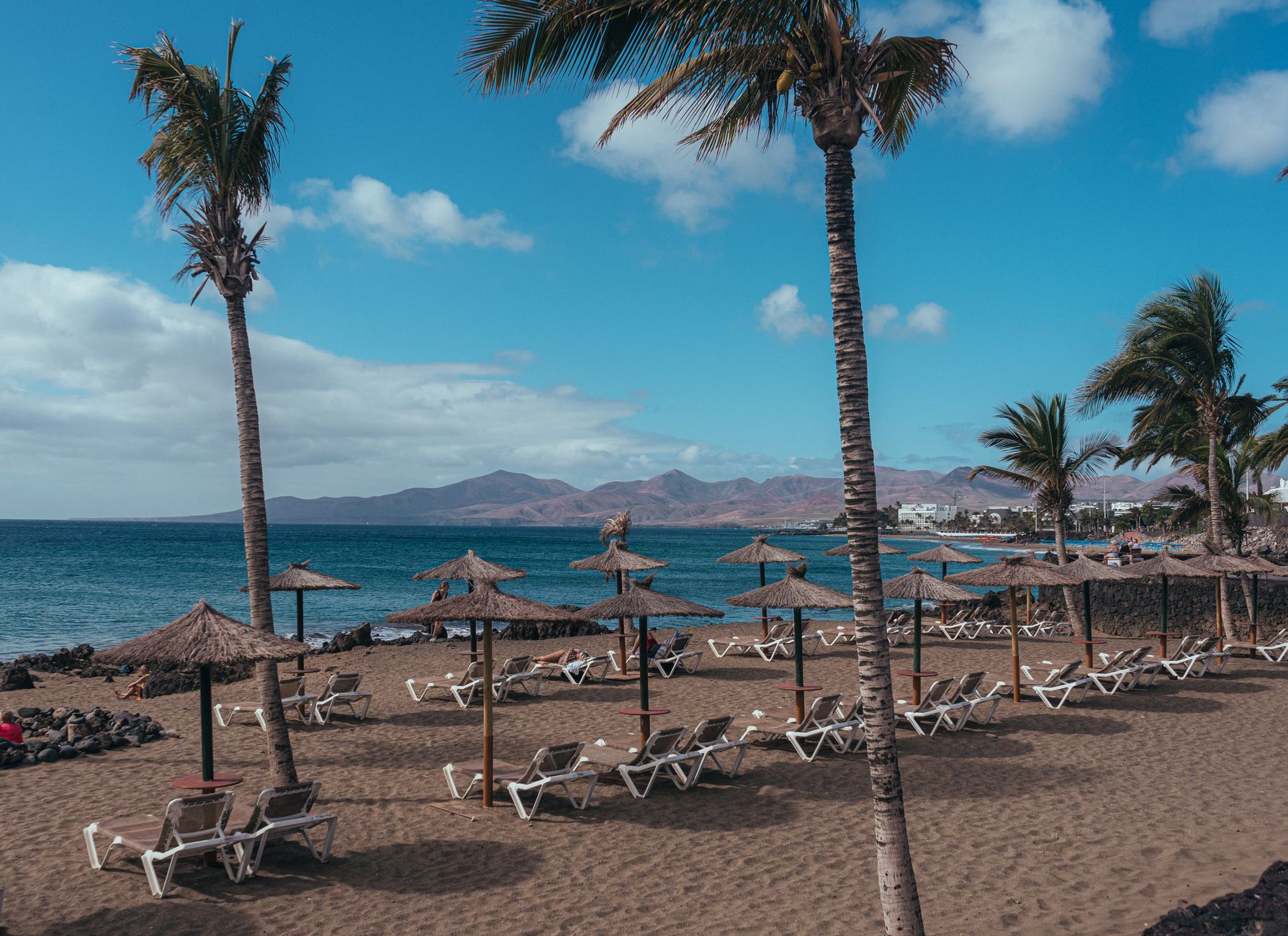 Puerto del Carmen in the municipality of Tías, Lanzarote, Spain — Relaxing tropical beach in Puerto del Carmen with sunbeds and palm tre
