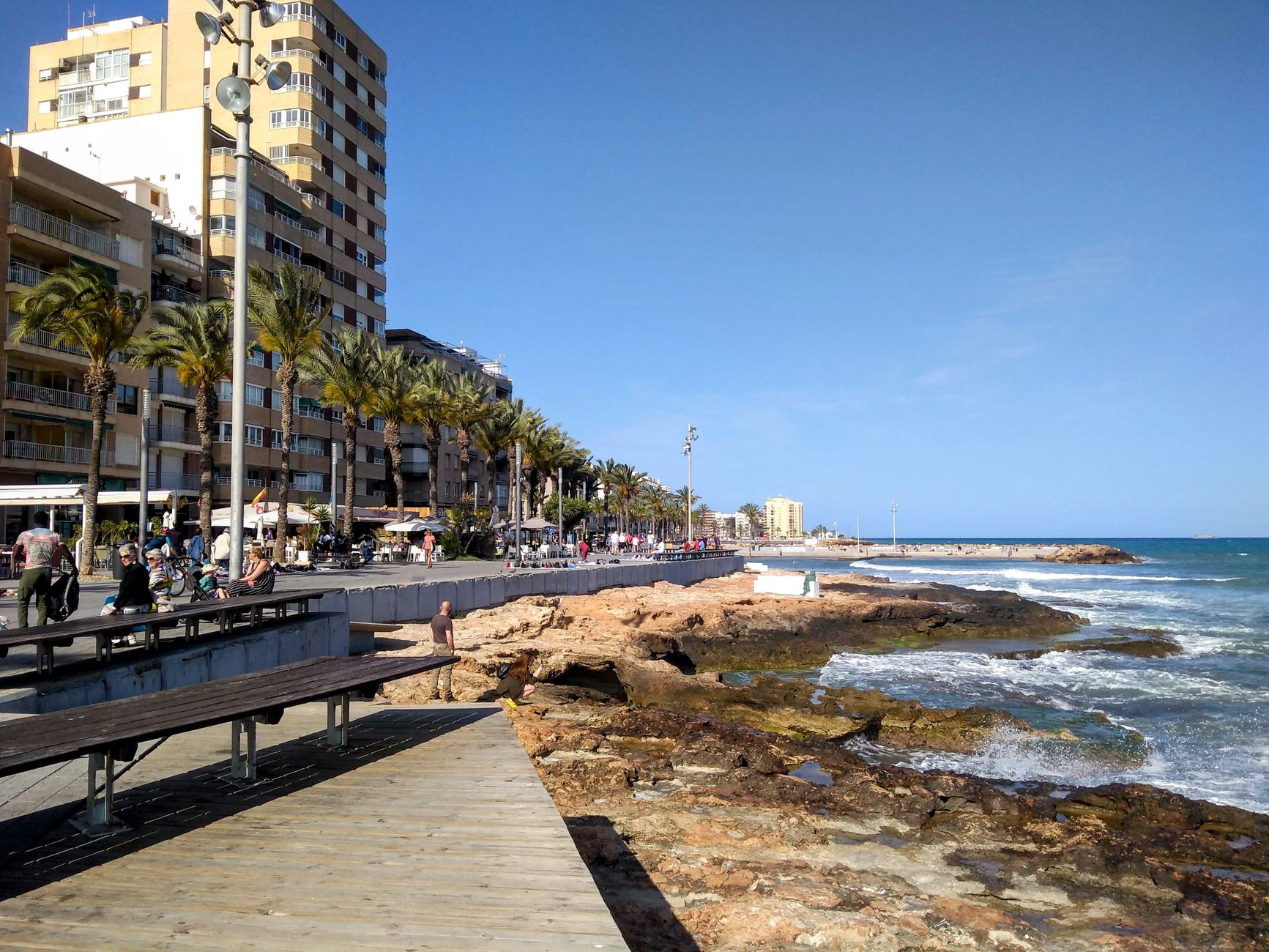 A view of Torrevieja's seafront promenade and beach on a sunny day, ideal for summer travel concepts.