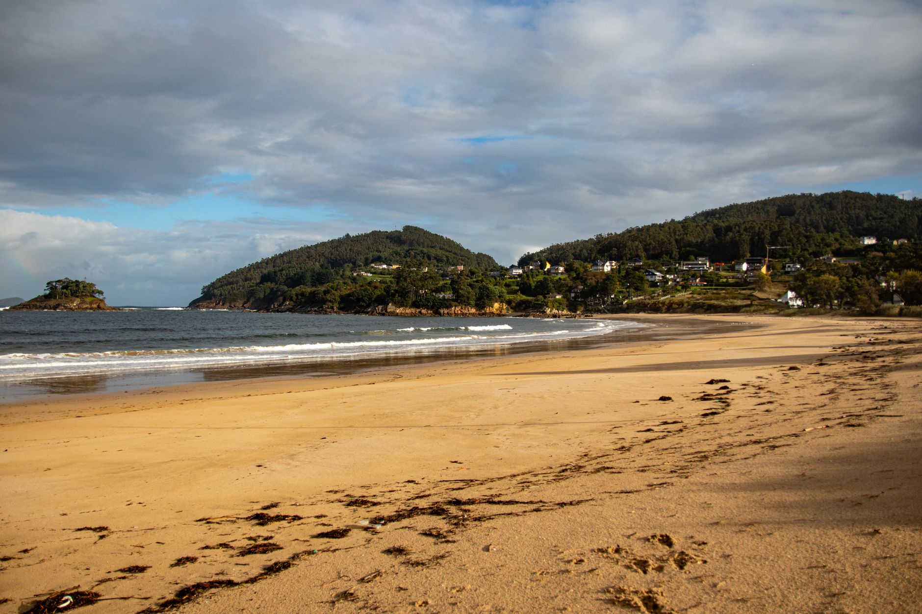 Beach scene in Viveiro, Galicia, Spain with cloudy sky and coastline.