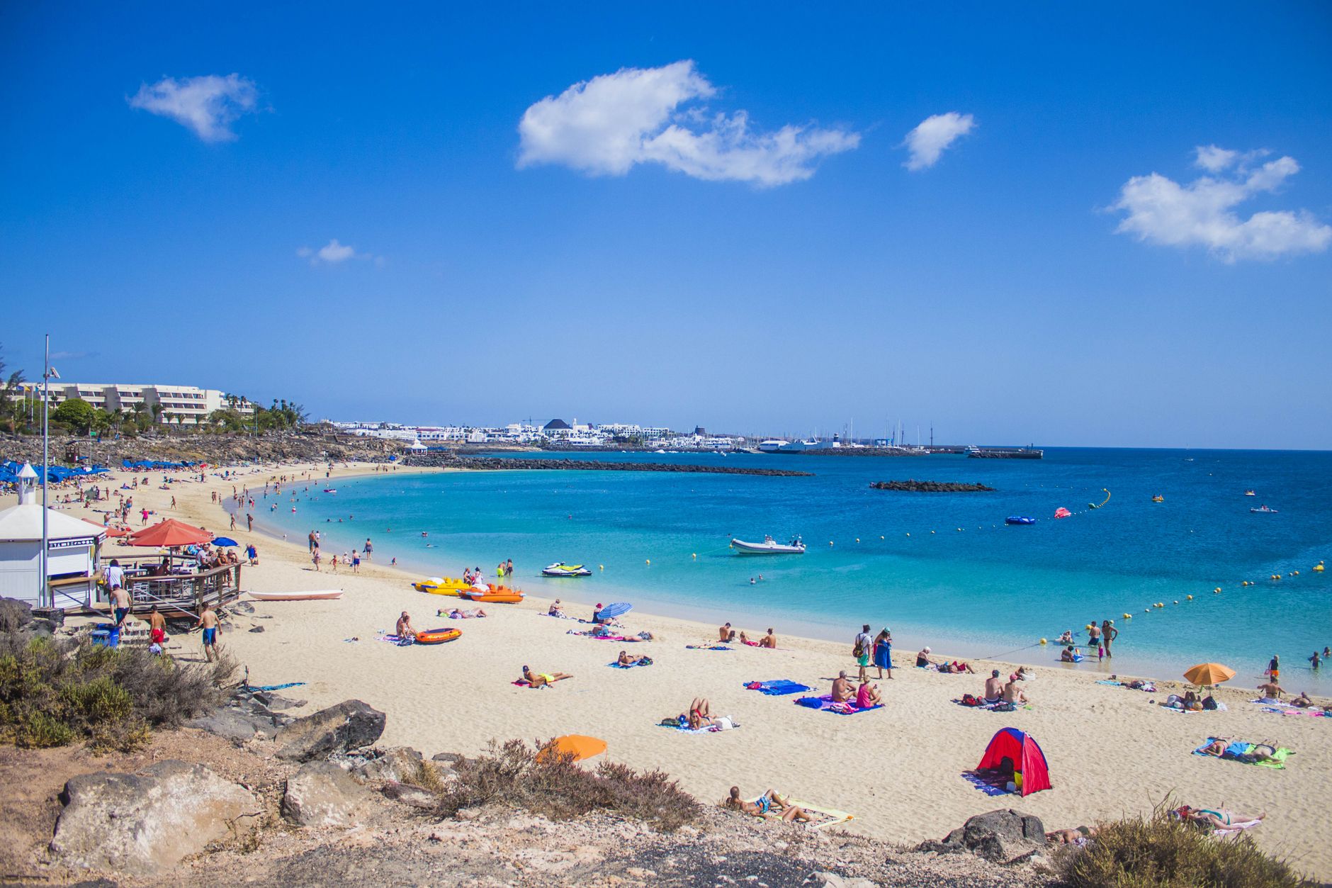 Playa Blanca in the municipality of Yaiza, Lanzarote, Spain — People enjoying a sunny day at Playa Blanca beach, Lanzarote with clea